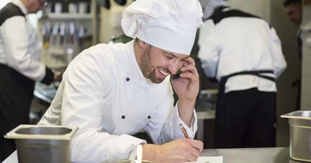 Chefkoch telefoniert mit Lieferanten, um die Lieferung seiner Küche zu planen.